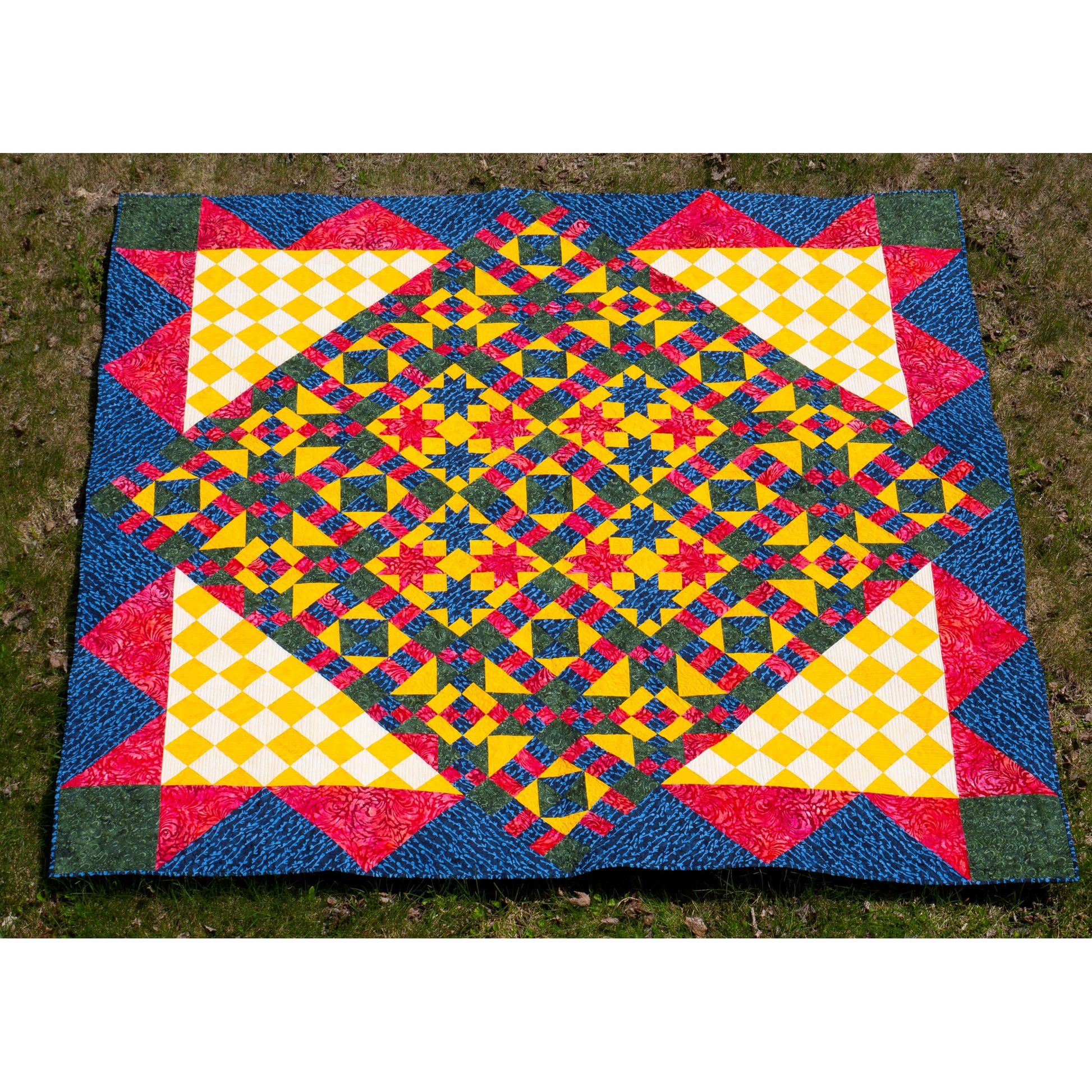 Colorful geometric-patterned quilt on a grassy background