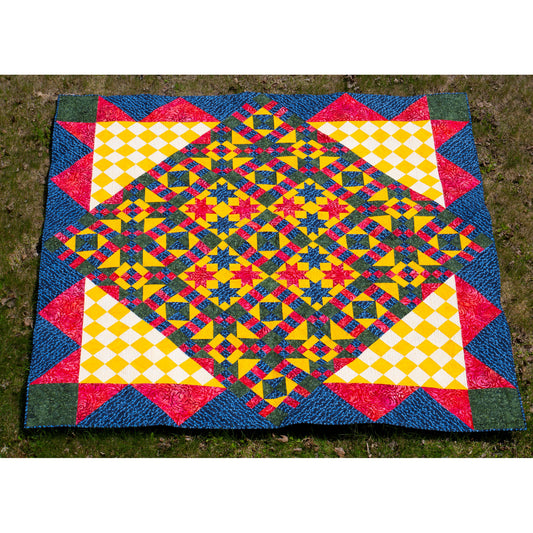 Colorful geometric-patterned quilt on a grassy background