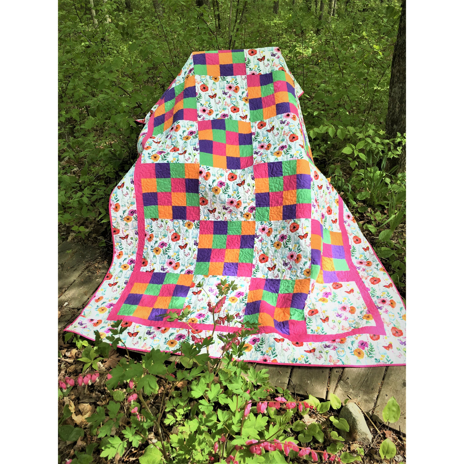 Colorful quilt with floral patterns draped over a tree stump in a forest setting