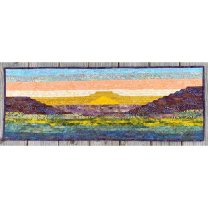 Quilt with landscape design featuring mountains and sky on a white background
