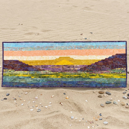 Colorful landscape quilt on a sandy surface with pebbles