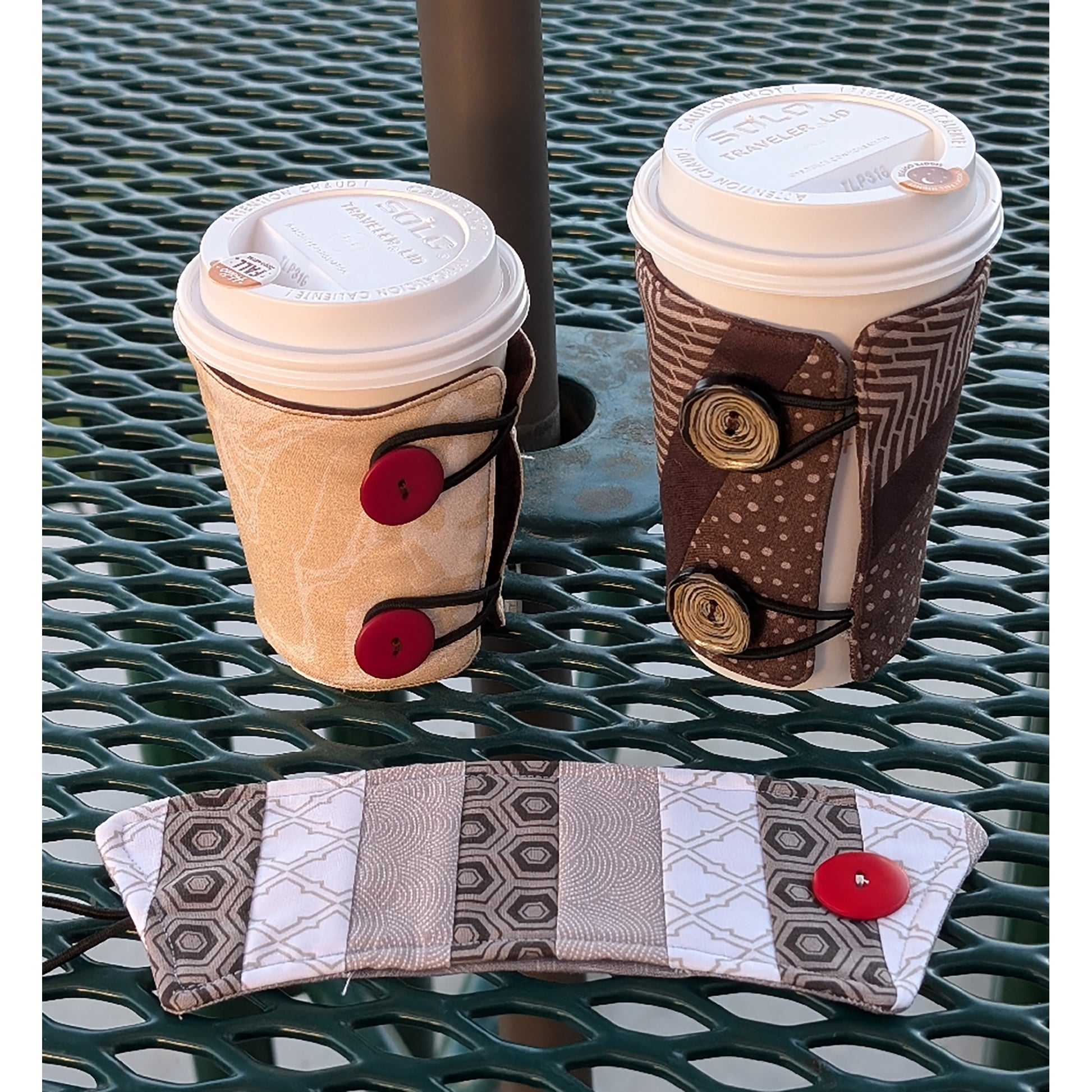 Two coffees from a restaurant in quilted holders with one shown in front. They are attached with buttons and elastic. Shown in multiple sizes.