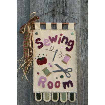 Decorative sign with 'Sewing Room' text and sewing-themed illustrations on a wooden background.