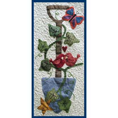 Decorative quilt with birds, butterfly, and ivy design on a textured background