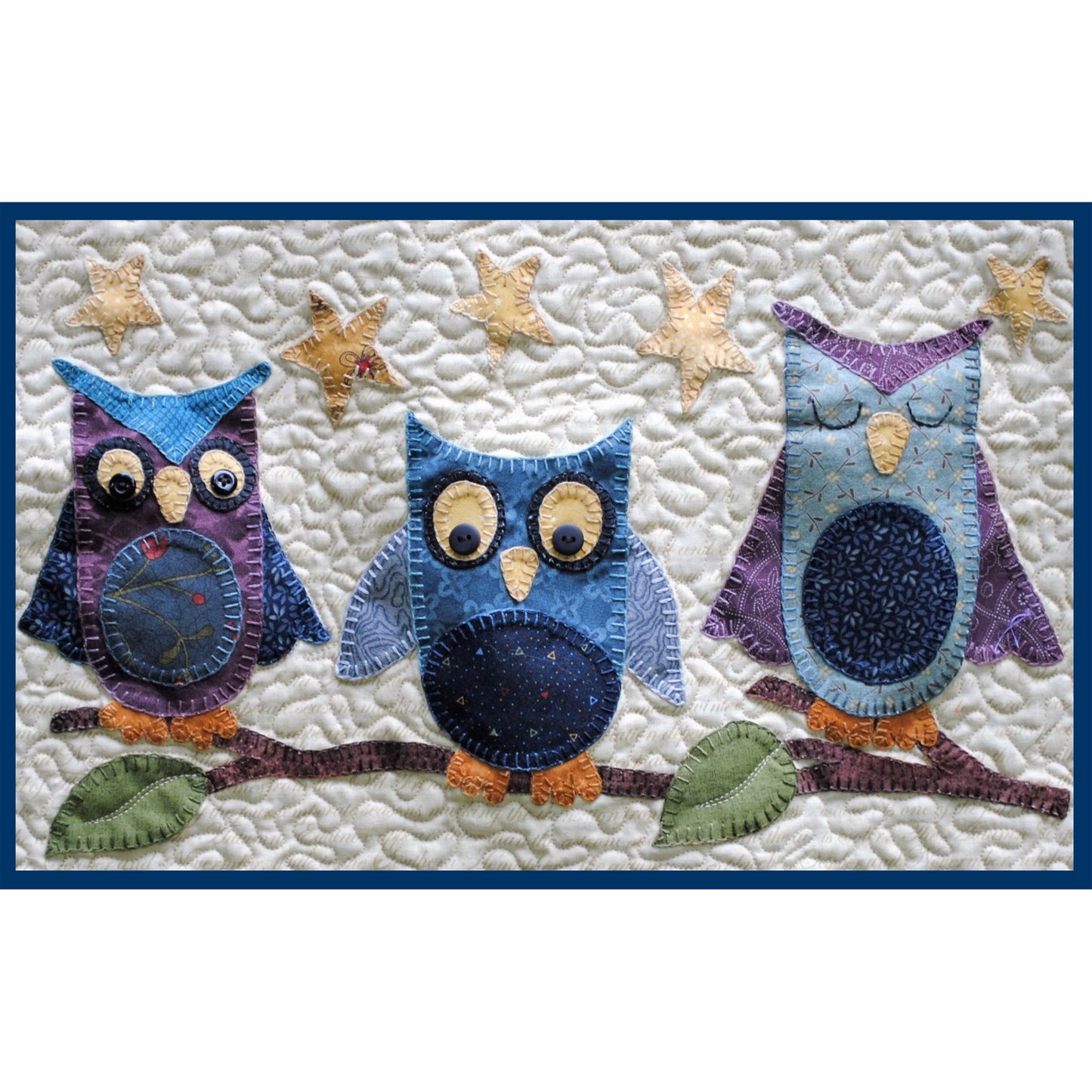 Quilt with three colorful owl designs on a white background